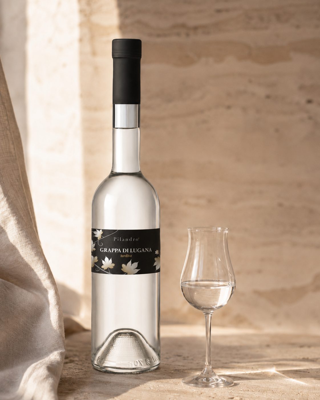 Flasche und Tulpenglas Grappa di Lugana Tardiva auf hellem Stein – Turbiana-Tresterbrand von Pilandro in Desenzano del Garda